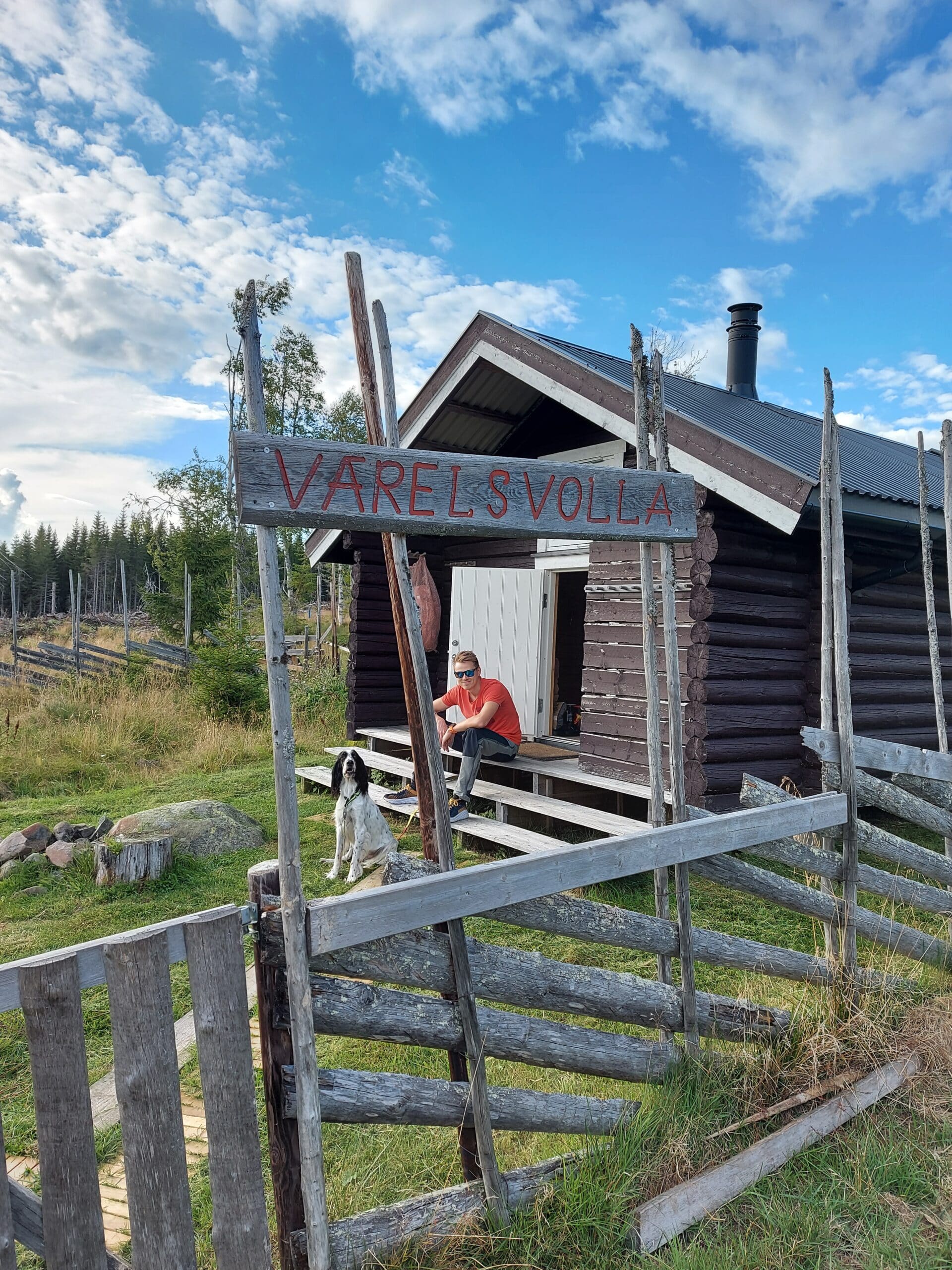 mann som sitter på trappa til koie innenfor skigard