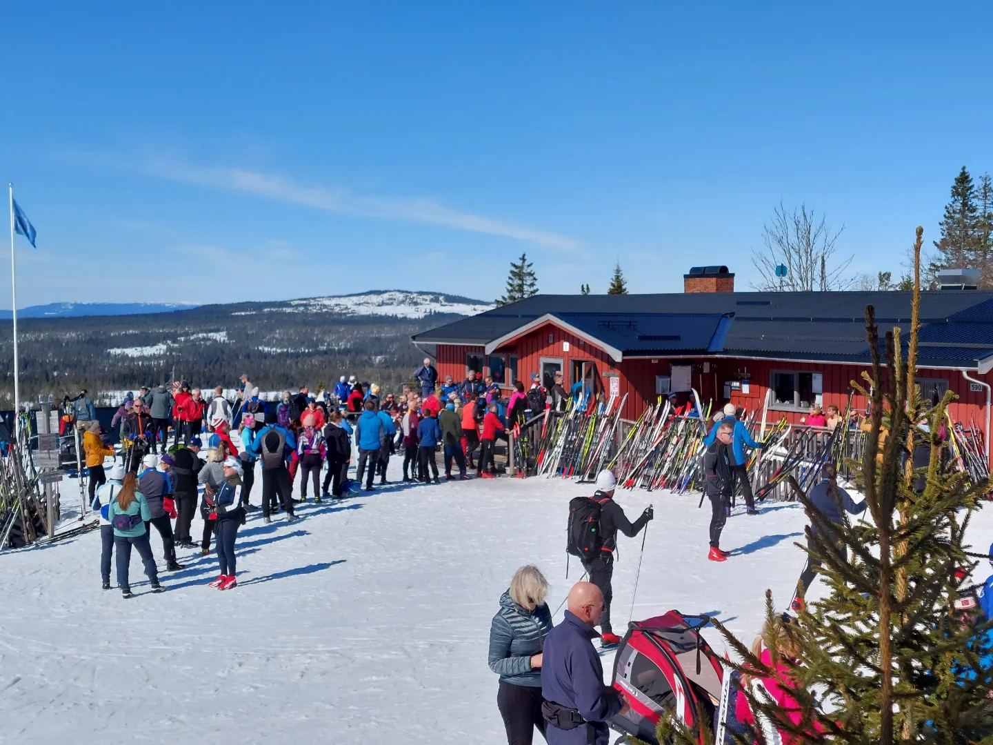 serveringshytte på fjellet med masse folk foran og blå himmel