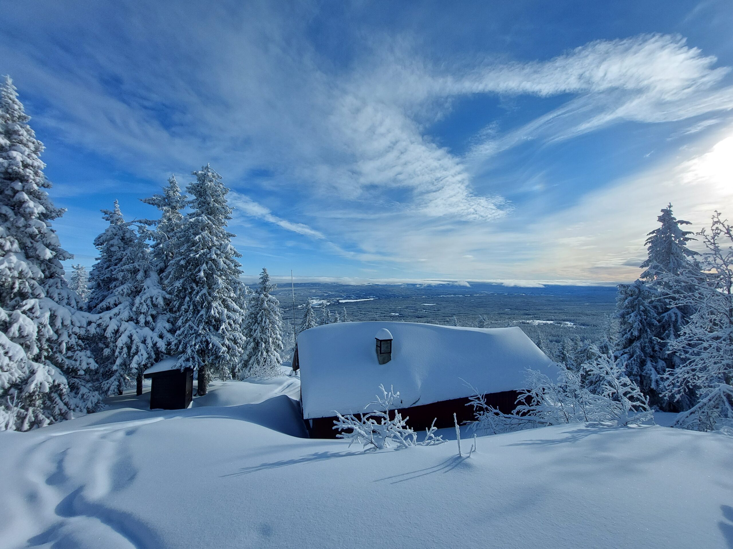 hytte dekket i urørt snø og blå himmel